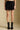 Front view of a woman wearing the Saltwater Luxe Andie Mini Skirt on a neutral background with black boots and hands at sides