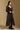 Model wearing the Saltwater Luxe Cyris Midi Dress in Black with a flowing skirt, side view