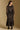 Model wearing the Saltwater Luxe Cyris Midi Dress in Black with a flowing skirt, back view