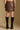 Model wearing the Saltwater Luxe Corin Mini Skirt in Chocolate showing chocolate faux-leather mini skirt, back view