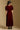 Model wearing the Saltwater Luxe Lorin Midi Dress in Burgundy with a flowing skirt, back view