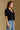 Model wearing the Saltwater Luxe Aeris Black Sweater showing black short-sleeve V-neck button-front sweater, side view