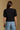 Model wearing the Saltwater Luxe Aeris Black Sweater showing black short-sleeve V-neck button-front sweater, back view