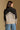 Model wearing the Saltwater Luxe Cain Natural Sweater with black colorblocking and chevron knit detail, back view