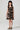 Girl model wearing Saltwater Luxe Littles Kayler Girls Mini Dress in Black Shell Print front full body studio view on grey background
