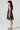 Girl model wearing Saltwater Luxe Littles Kayler Girls Mini Dress in Black Shell Print side full body studio view