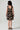 Girl model wearing Saltwater Luxe Littles Kayler Girls Mini Dress in Black Shell Print back full body studio view on grey background