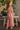 Back view of girl wearing the Lucca Jumper in a pink striped print featuring flutter sleeves, an open-back detail, and wide-leg pants