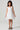 Girl model wearing Saltwater Luxe Littles Kayler Girls Mini Dress in White Eyelet front full body studio view on grey background