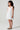 Girl model wearing Saltwater Luxe Littles Kayler Girls Mini Dress in White Eyelet side full body studio view
