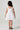 Girl model wearing Saltwater Luxe Littles Kayler Girls Mini Dress in White Eyelet back full body studio view on grey background