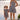 A woman and a young girl wearing matching strapless gingham mini dresses stand hand in hand by a lake. The woman wears a white cowboy hat and tall beige boots, while the girl wears dark boots and white socks