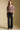 Full body front view of a woman wearing the Saltwater Luxe Robyn Top on a neutral background with black pants and sneakers