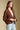 Side angle view of a woman wearing the Saltwater Luxe Aden Sweater and jeans on a neutral background with hands clasped 