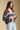 Side angle view of a woman wearing the Saltwater Luxe Aden Sweater on a neutral background with jeans and hands clasped