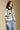 Side angle view of a woman wearing the Saltwater Luxe Alamere Sweater on a neutral background with arms lowered 