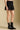 Side angle view of a woman wearing the Saltwater Luxe Andie Mini Skirt on a neutral background with black boots.