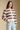 Side angle view of a woman wearing the Saltwater Luxe Arella Sweater on a neutral background with hand in pocket