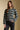 Front view of a woman wearing the Saltwater Luxe Arella Sweater on a neutral background with hand in pocket of black pants