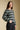 Side angle view of a woman wearing the Saltwater Luxe Arella Sweater on a neutral background with hand in pocket