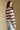 Side angle view of a woman wearing the Saltwater Luxe Arella Sweater on a neutral background looking over one shoulder