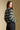 Side angle view of a woman wearing the Saltwater Luxe Arella Sweater on a neutral background looking over one shoulder