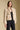 Side angle view of a woman wearing the Saltwater Luxe Ash Jacket on a neutral background over black outfit