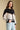 Side angle view of a woman wearing the Saltwater Luxe Azure Sweater on a neutral background with hand in jeans pocket