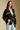 Side angle view of a woman wearing the Saltwater Luxe Birdy Sweater on a neutral background with hand in pocket