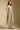Side angle view of a woman wearing the Saltwater Luxe Calystah Midi Dress on a neutral background with boots