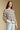 Side angle view of a woman wearing the Saltwater Luxe Camron Sweater on a neutral background with hand in pocket and one lowered