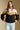 Front view of a woman wearing the Saltwater Luxe Camron Sweater on a neutral background with hands on hem of sweater
