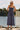 Front view of a woman wearing the Salt Water Luxe Charlize Midi Dress on a dock in front of water