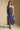 Front view of a woman wearing the Salt Water Luxe Charlize Midi Dress on a neutral background with cap ad sneakers