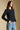 Side angle view of a woman wearing the Saltwater Luxe Verity Sweater on a neutral background with pants
