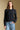 Front view of a woman wearing the Saltwater Luxe Verity Sweater on a neutral background with hand in pocket