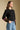 Side angle view of a woman wearing the Saltwater Luxe Darra Sweater on a neutral background with hand in pocket of jeans