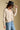 Side angle view of a woman wearing the Saltwater Luxe Dovere Sweater on a neutral background with bluejeans