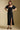 Front view of a woman wearing the Saltwater Luxe Drew Midi Dress and shoes on a neutral background with hands on hips