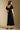 Back view of a woman wearing the Saltwater Luxe Drew Midi Dress on a neutral background