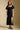 Front view of a woman wearing the Saltwater Luxe Drew Midi Dress and sneakers on a neutral background 