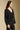 Side angle view of a woman wearing the Saltwater Luxe Ellyn Sweater on a neutral background with arms lowered