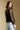 Back view of a woman wearing the Saltwater Luxe Evrra Top on a neutral background looking over one shoulder