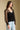 Side angle view of a woman wearing the Saltwater Luxe Evrra Top on a neutral background with jeans