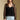 Side angle view of a woman wearing the Saltwater Luxe Evrra Top on a neutral background with blue jeans