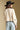 Back view of a woman wearing the Saltwater Luxe  Fiorra Sweater on a neutral background with hat