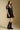 Side angle view of a woman wearing the Saltwater Luxe Ginna Mini Dress on a neutral background with hands at sides