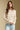 Front view of a woman wearing the Saltwater Luxe Hadlee Sweater on a neutral background with hands clasped