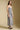 Side angle view of a woman wearing the Saltwater Luxe Harisyn Midi Dress on a neutral background with hands lowered