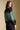 Back view of a woman wearing the Saltwater Luxe Isabeau Sweater on a neutral background looking over one shoulder